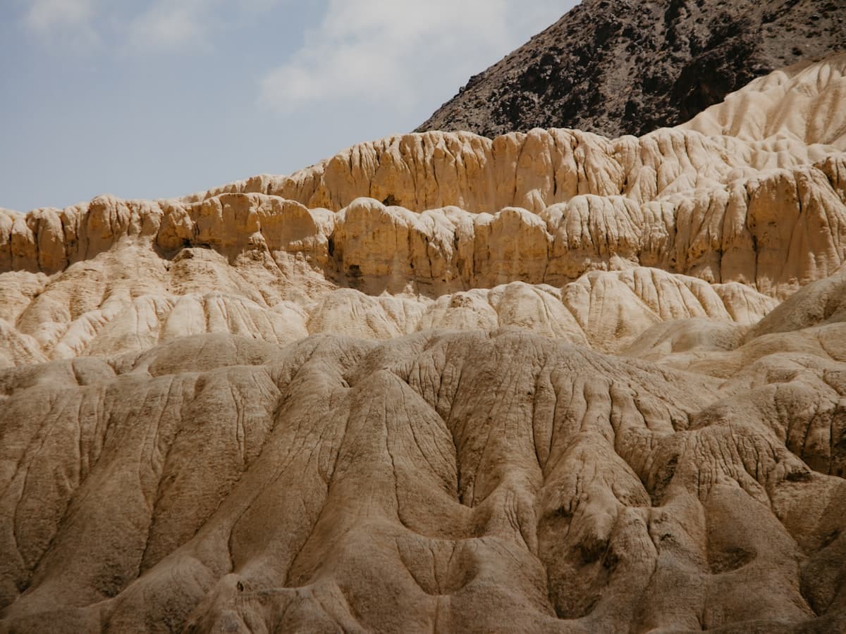 Pale, wind-eroded slopes fold into ridge after ridge under a thin high-altitude sky — Ladakh's lunar badland country.