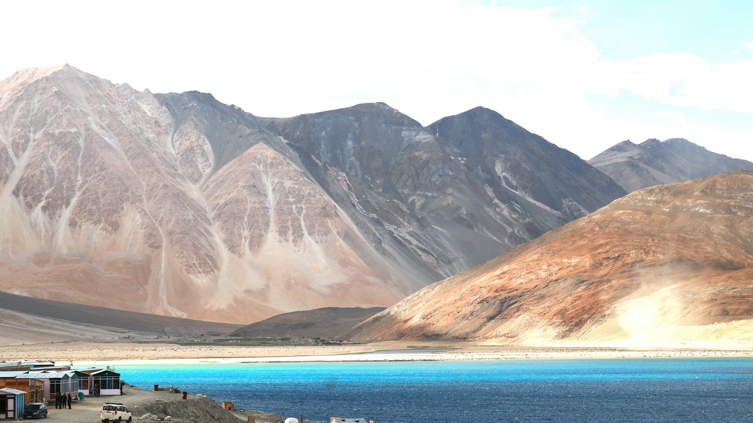 A broad sheet of high-altitude water lies cupped by range upon range of raw Himalayan mountains in Ladakh.