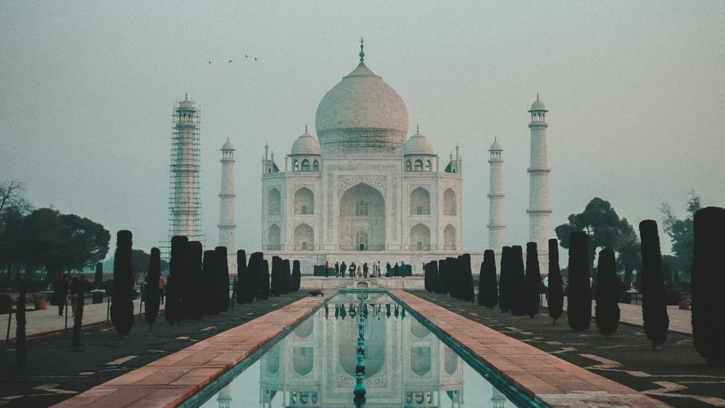 The Taj Mahal in full symmetry, its dome, minarets and gateway doubled in the still water of the central channel below.