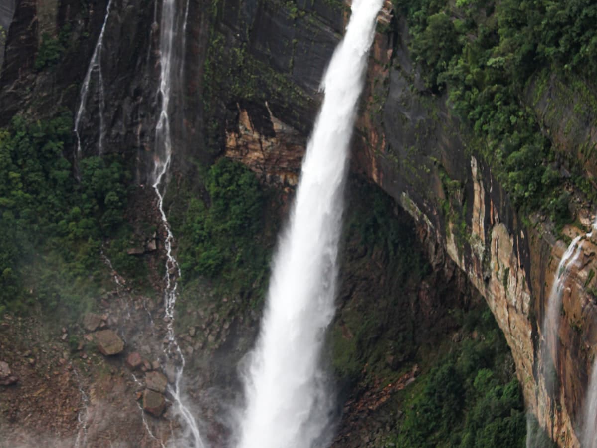 The single tall plunge of Nohkalikai Falls dropping down a green cliff into a pool near Cherrapunji, Meghalaya.