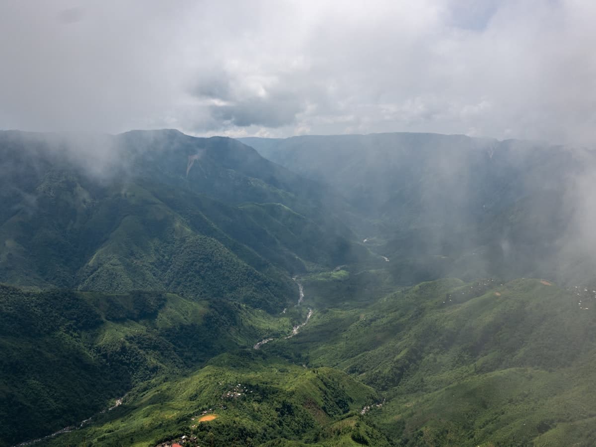 Misty green ridges falling away into a deep river valley at Laitlum Canyons near Shillong, Meghalaya.