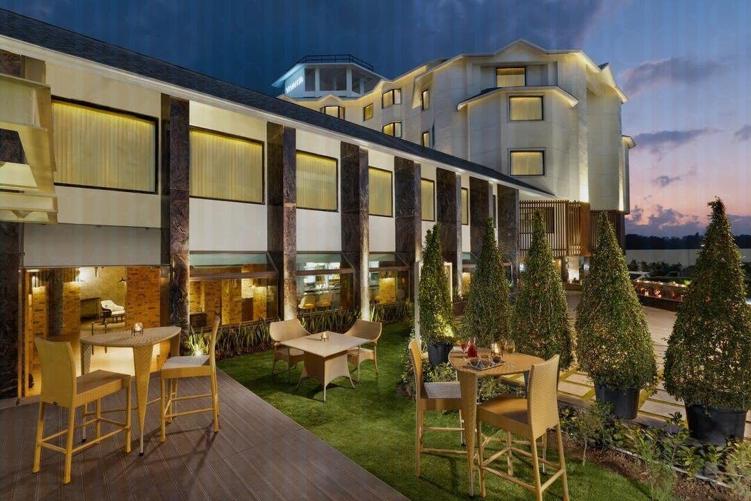 The glass-walled restaurant and terrace of Vivanta Meghalaya, Shillong lit at dusk.
