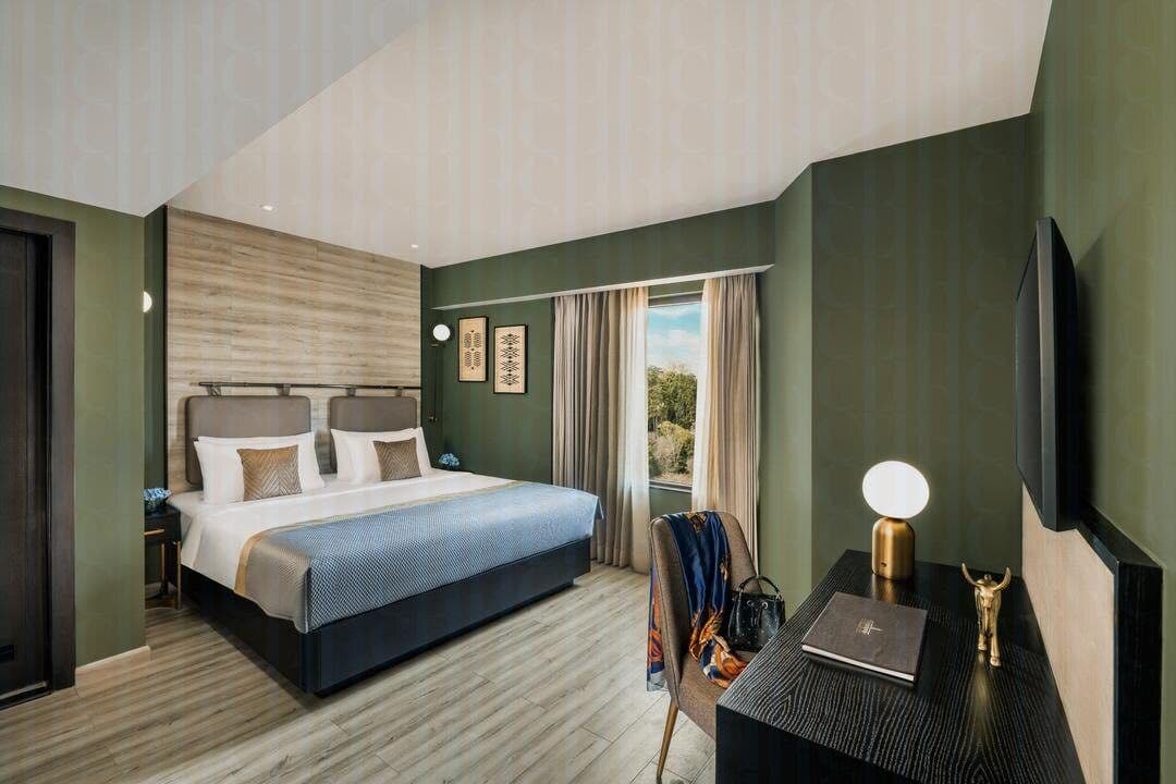 A green-walled guest room at Vivanta Meghalaya, Shillong with a king bed and timber flooring.