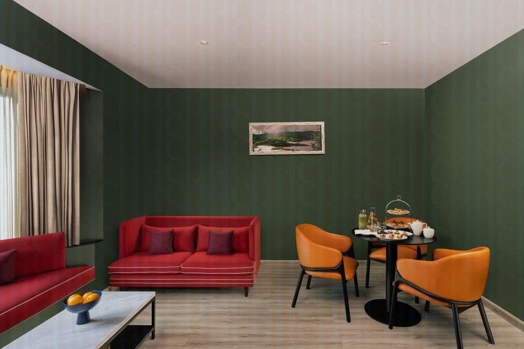 The living area of a Vivanta Meghalaya, Shillong suite with a red sofa and an afternoon-tea setting.
