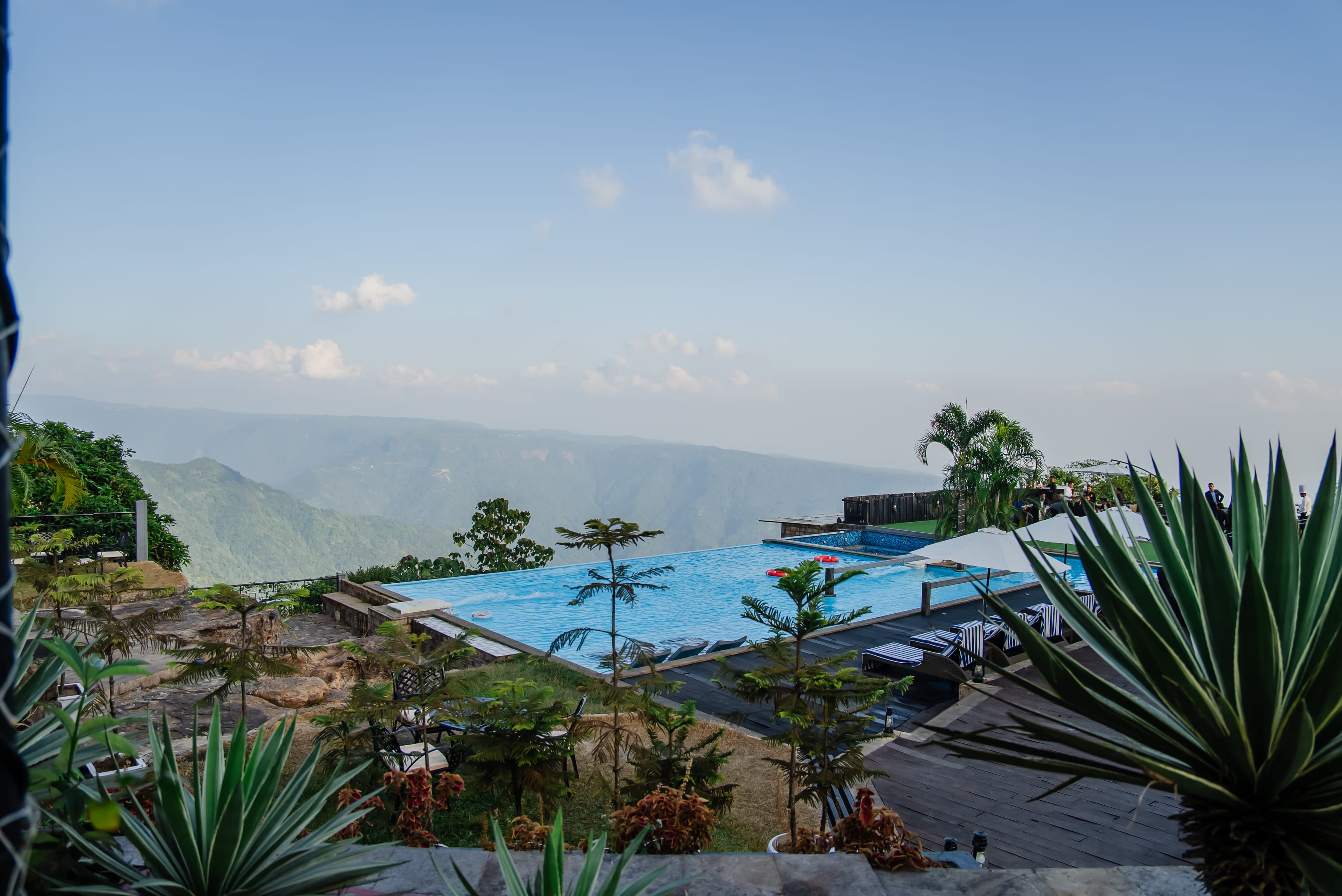 The infinity pool and loungers at Polo Orchid Resort, Cherrapunji overlooking forested valley ridges.