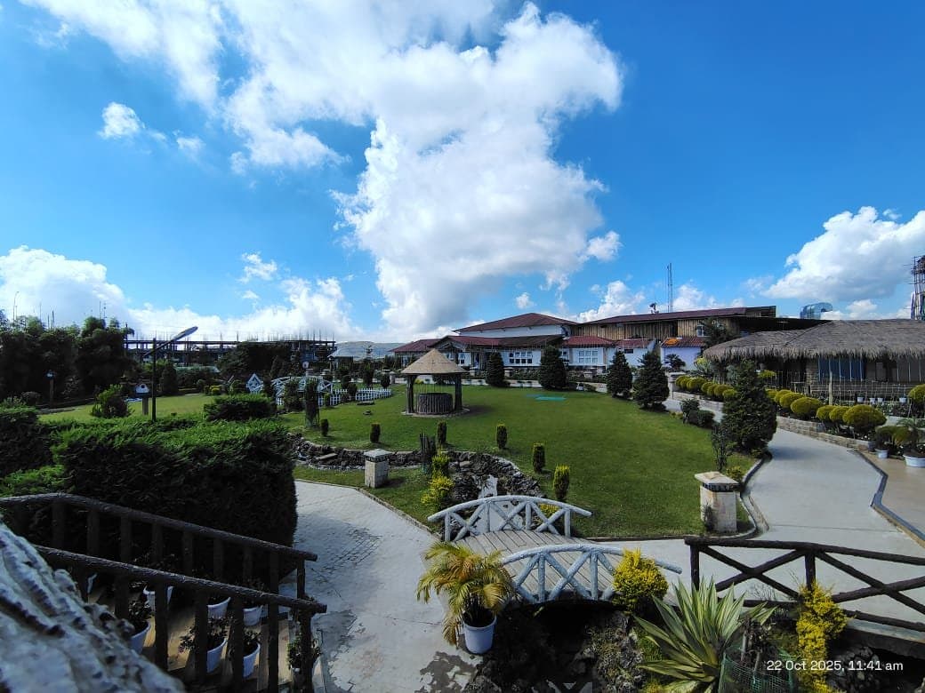 A wider view of Jiva Resort, Sohra with its terraced gardens and pathways below the hillside building.