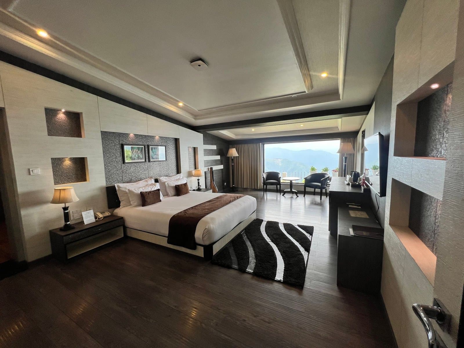 A Premium Luxury Suite bedroom at Jiva Resort, Sohra with a double bed facing a mountain-view window.