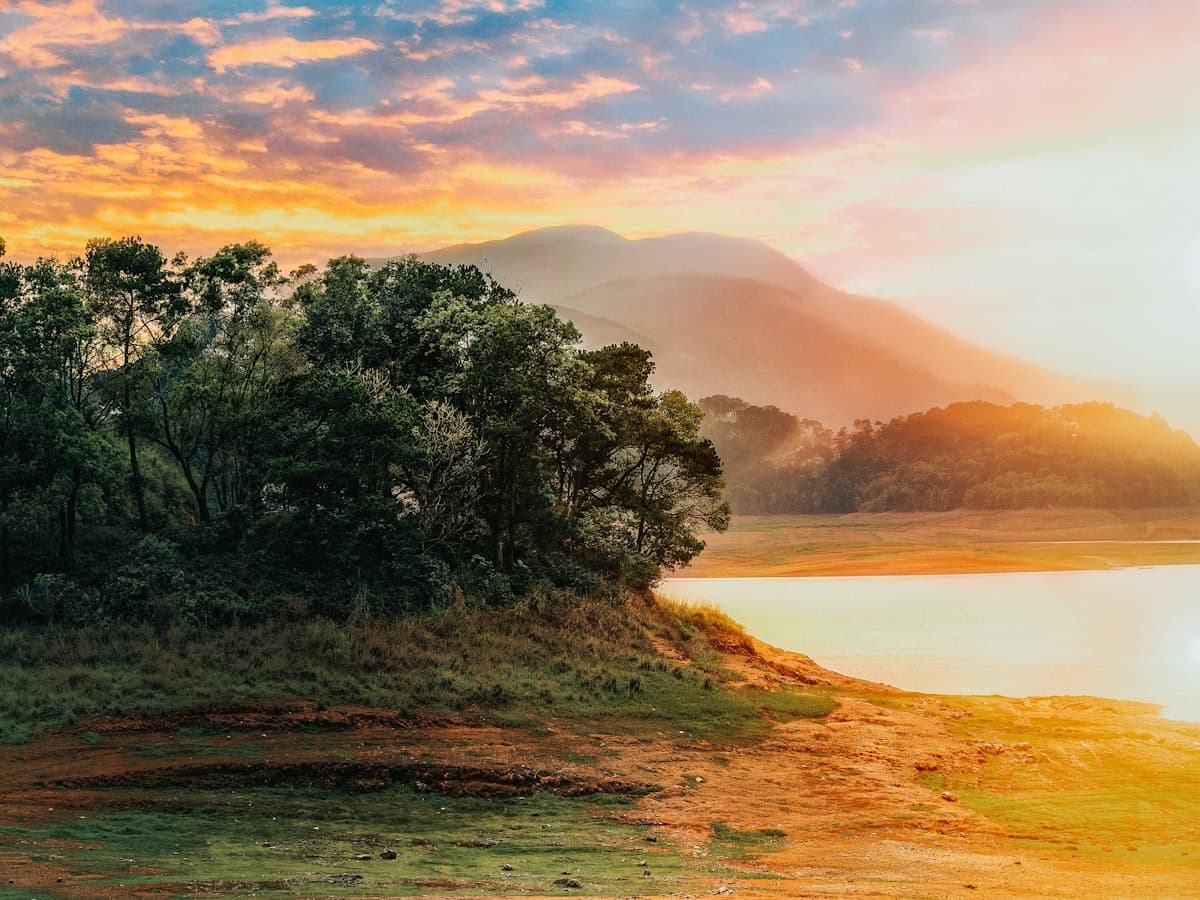 A green field above Umiam Lake near Shillong under an orange and blue sunset sky.