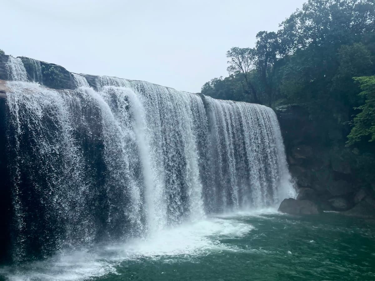 Krang Suri Falls pouring over dark rock into its plunge pool in the Jaintia Hills.