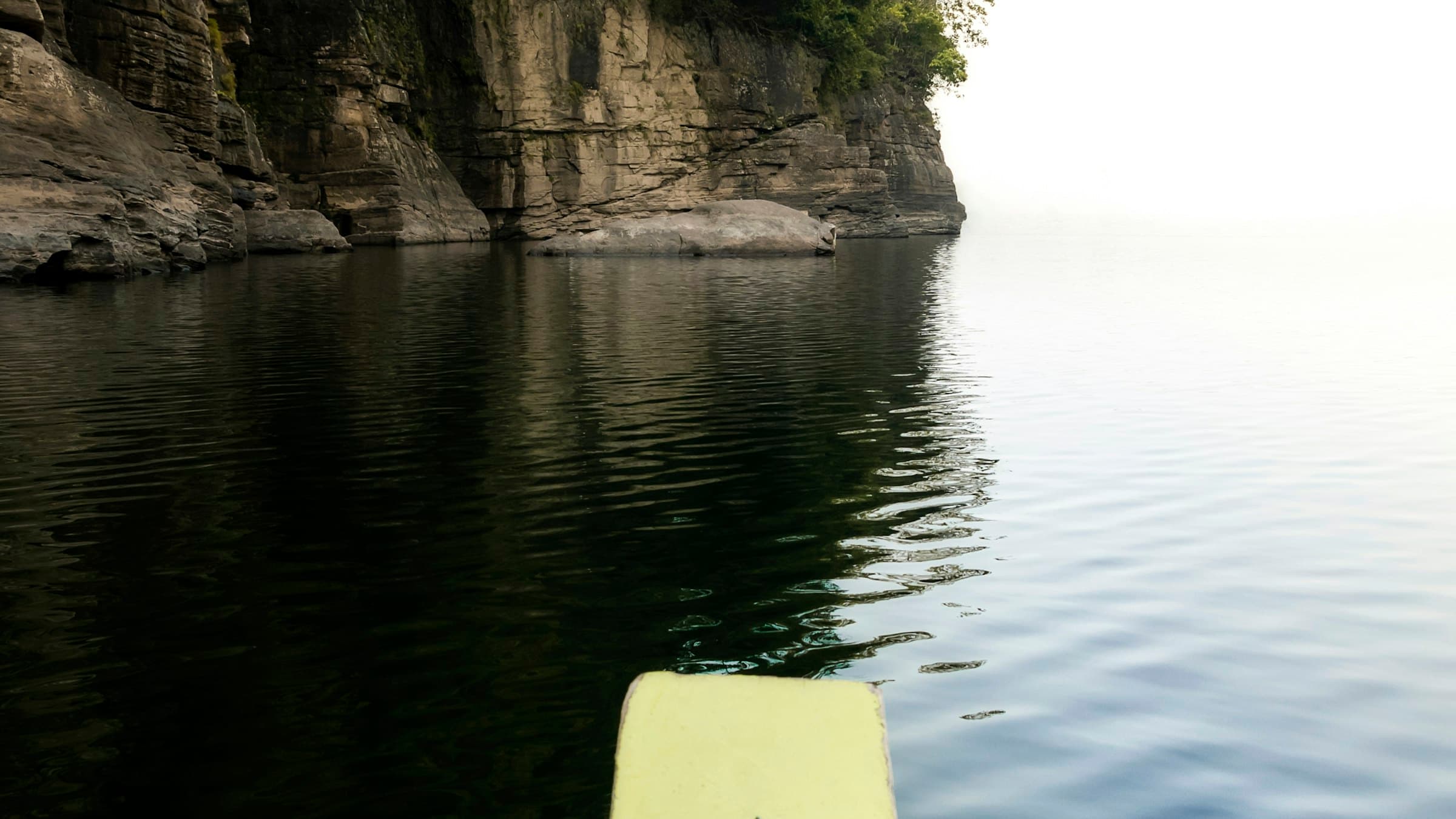 The glass-clear Dawki River seen from a boat in the early morning, hills on both banks.