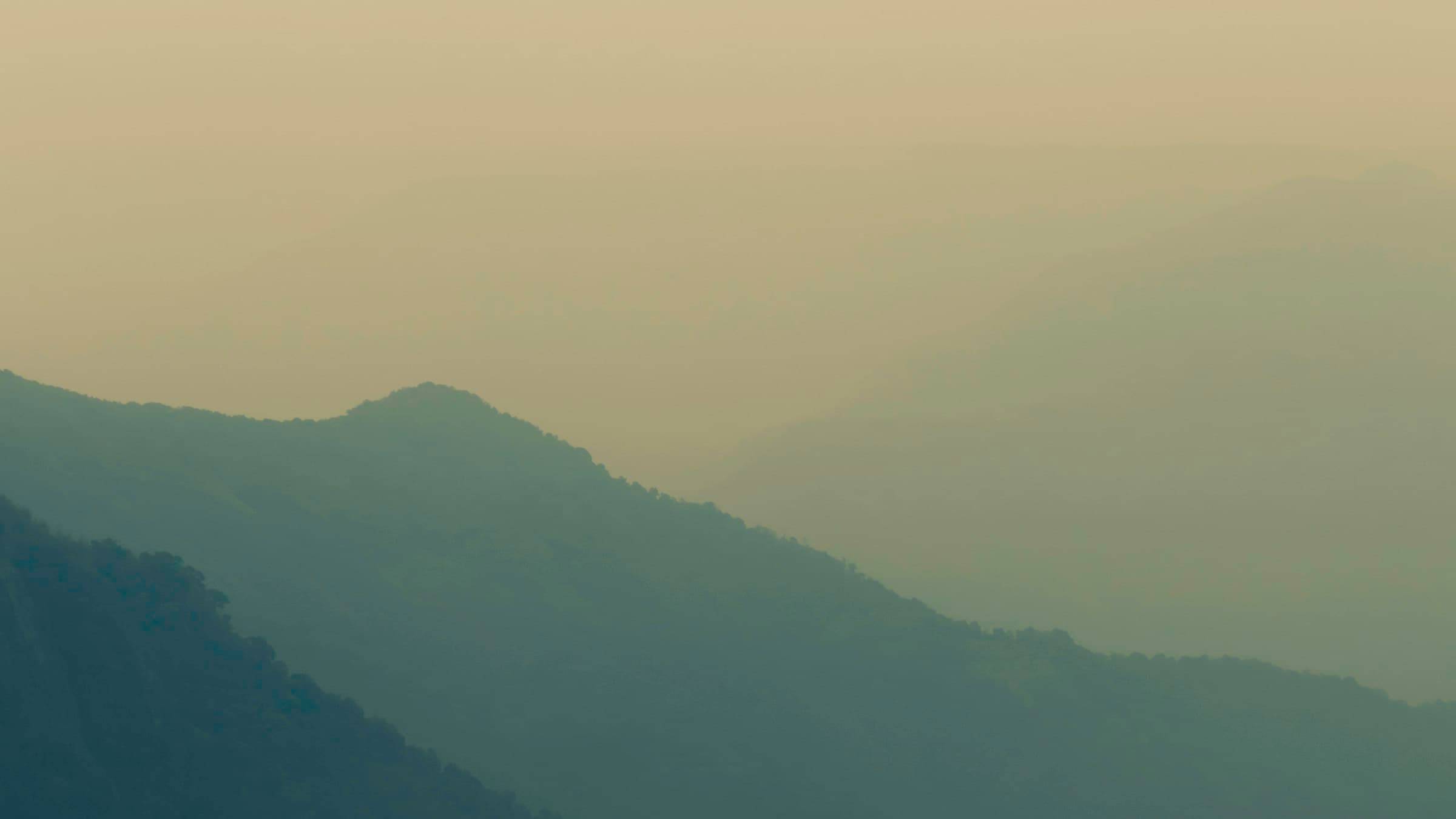 Layered green ridges of the Khasi Hills fading into cloud under an overcast sky.
