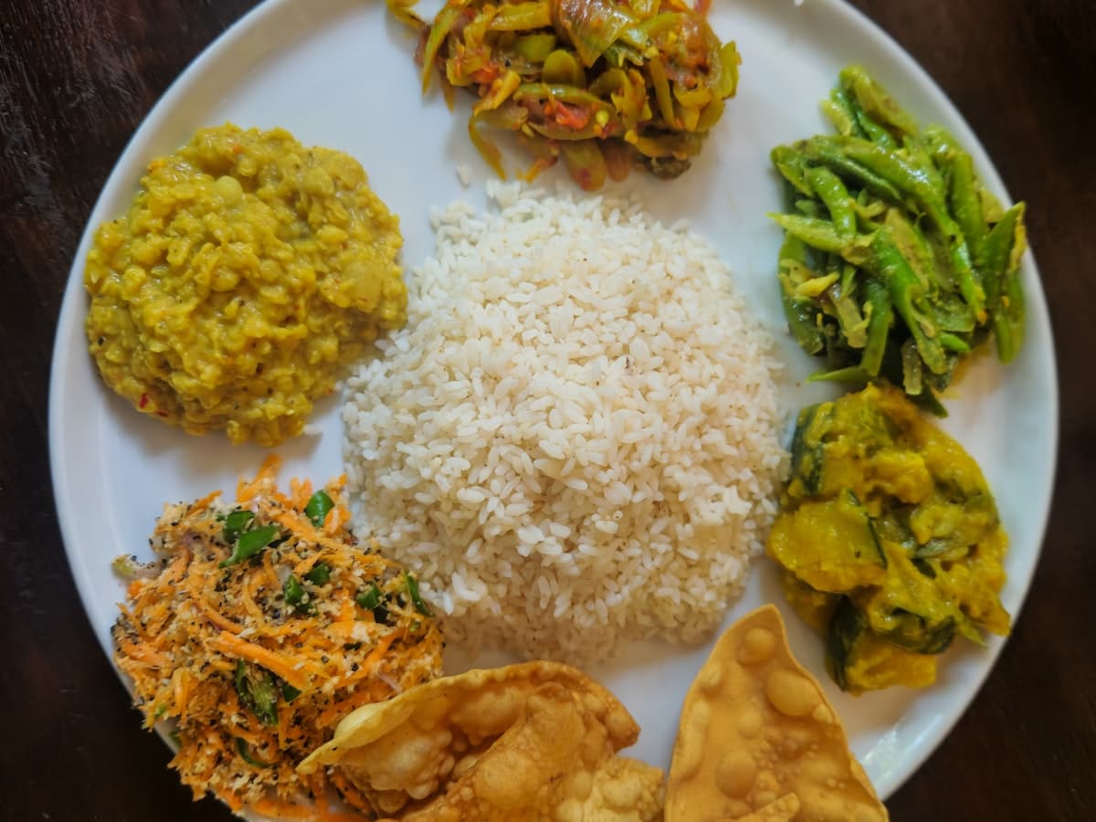 A plate of rice with an assortment of South Asian meat and vegetable dishes.