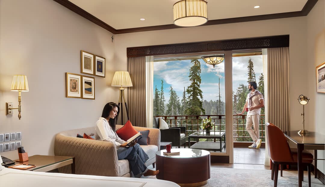 A suite living area at The Khyber Himalayan Resort & Spa with carved furniture and mountain-view windows.