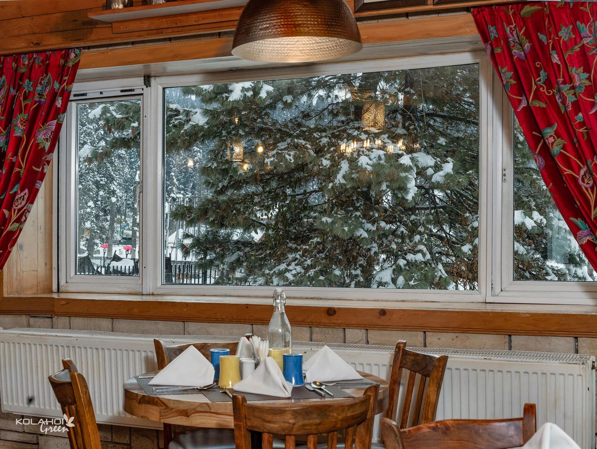 The wood-panelled in-house restaurant at Kolahoi Green Heights, Gulmarg with laid tables.