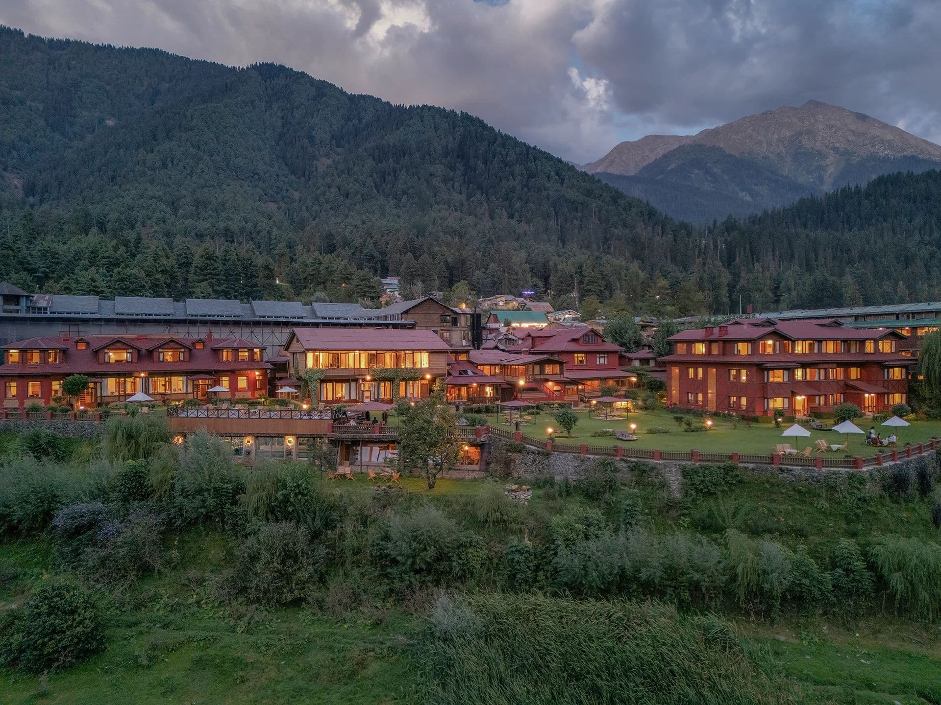 Pahalgam Hotel at dusk, its red-roofed blocks set among lawns below the mountains.