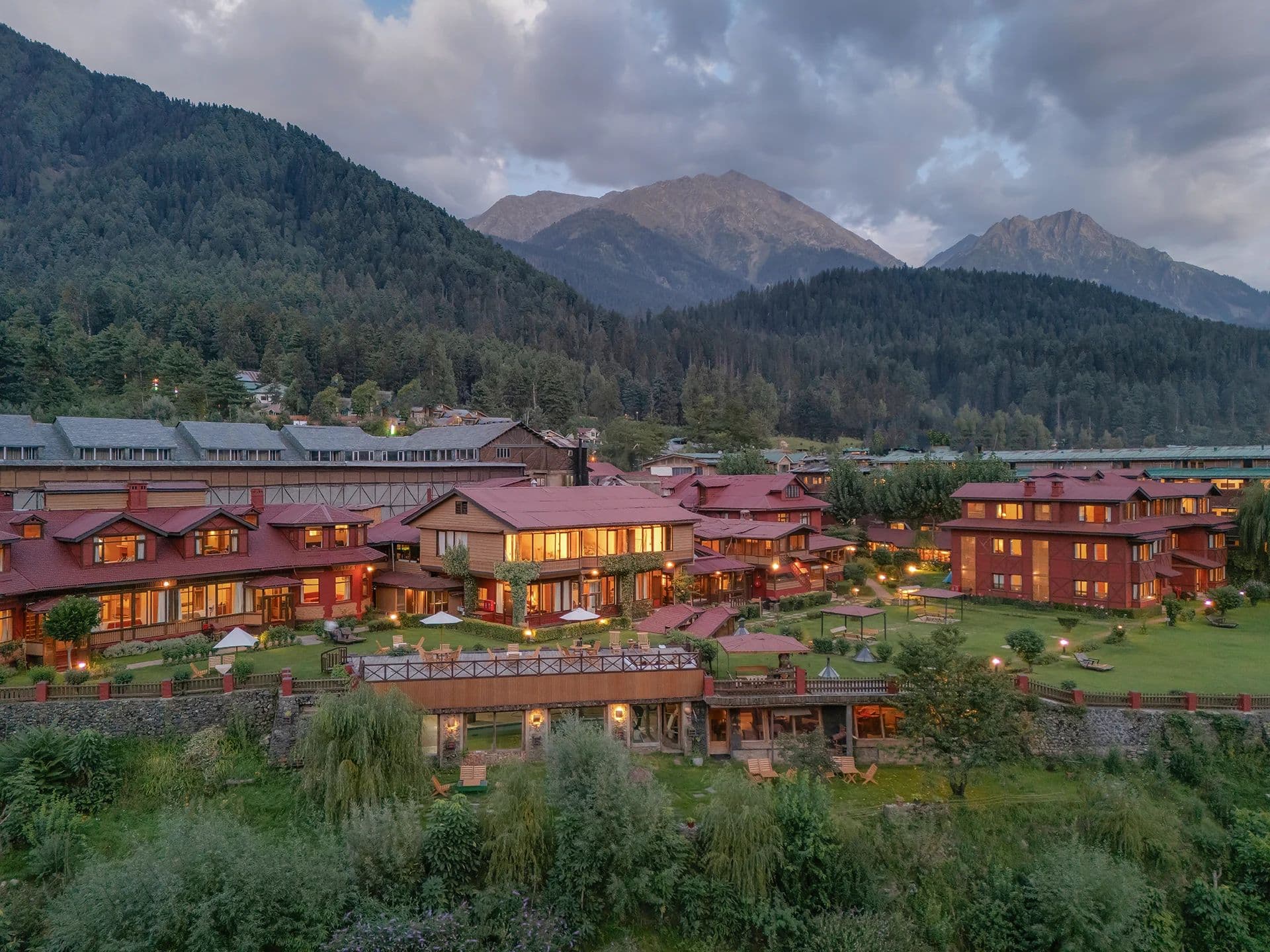 The lit blocks of Pahalgam Hotel at dusk with the surrounding mountains.