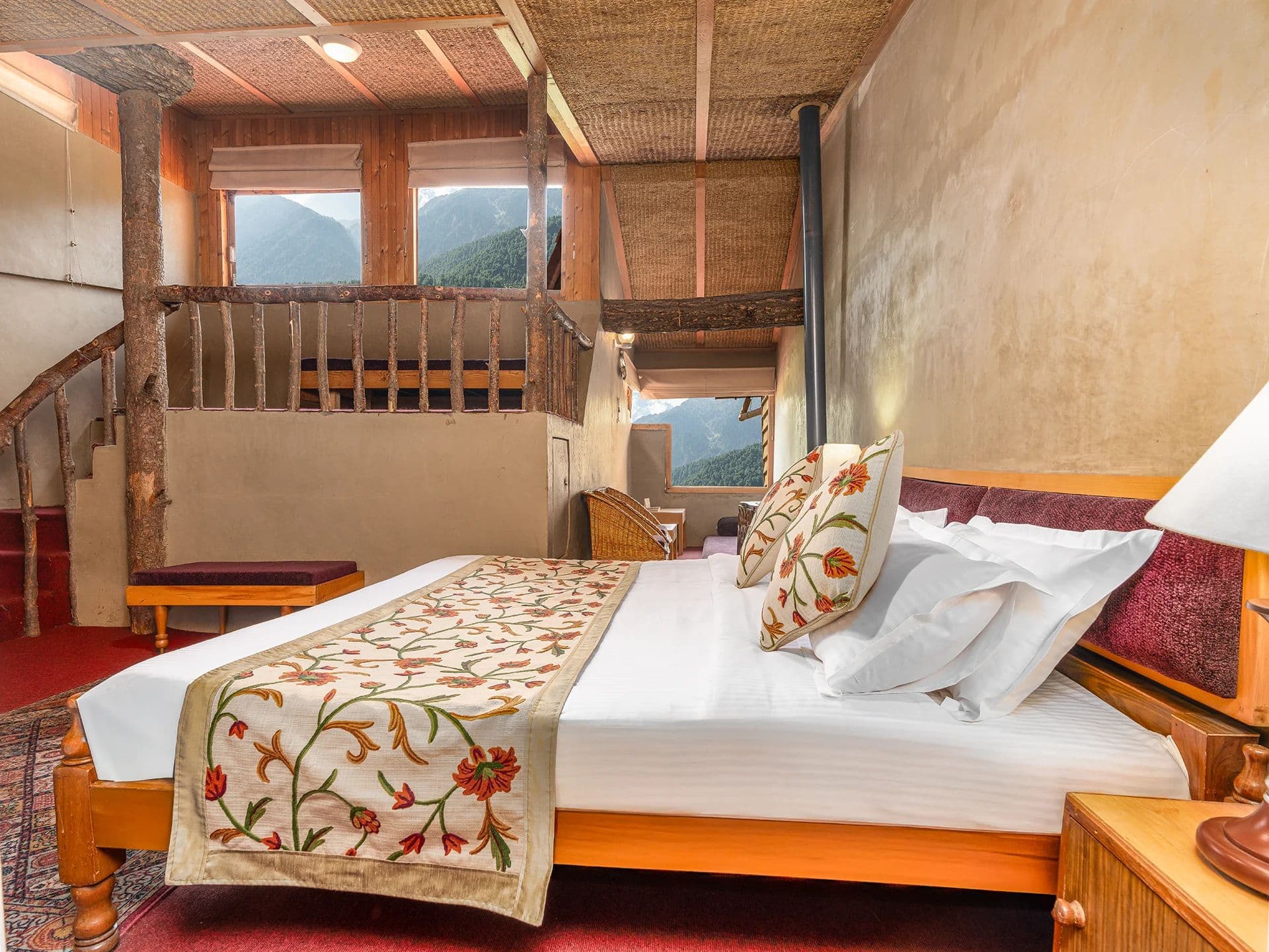A Deluxe room at Pahalgam Hotel with white bedding and wood-panelled walls.