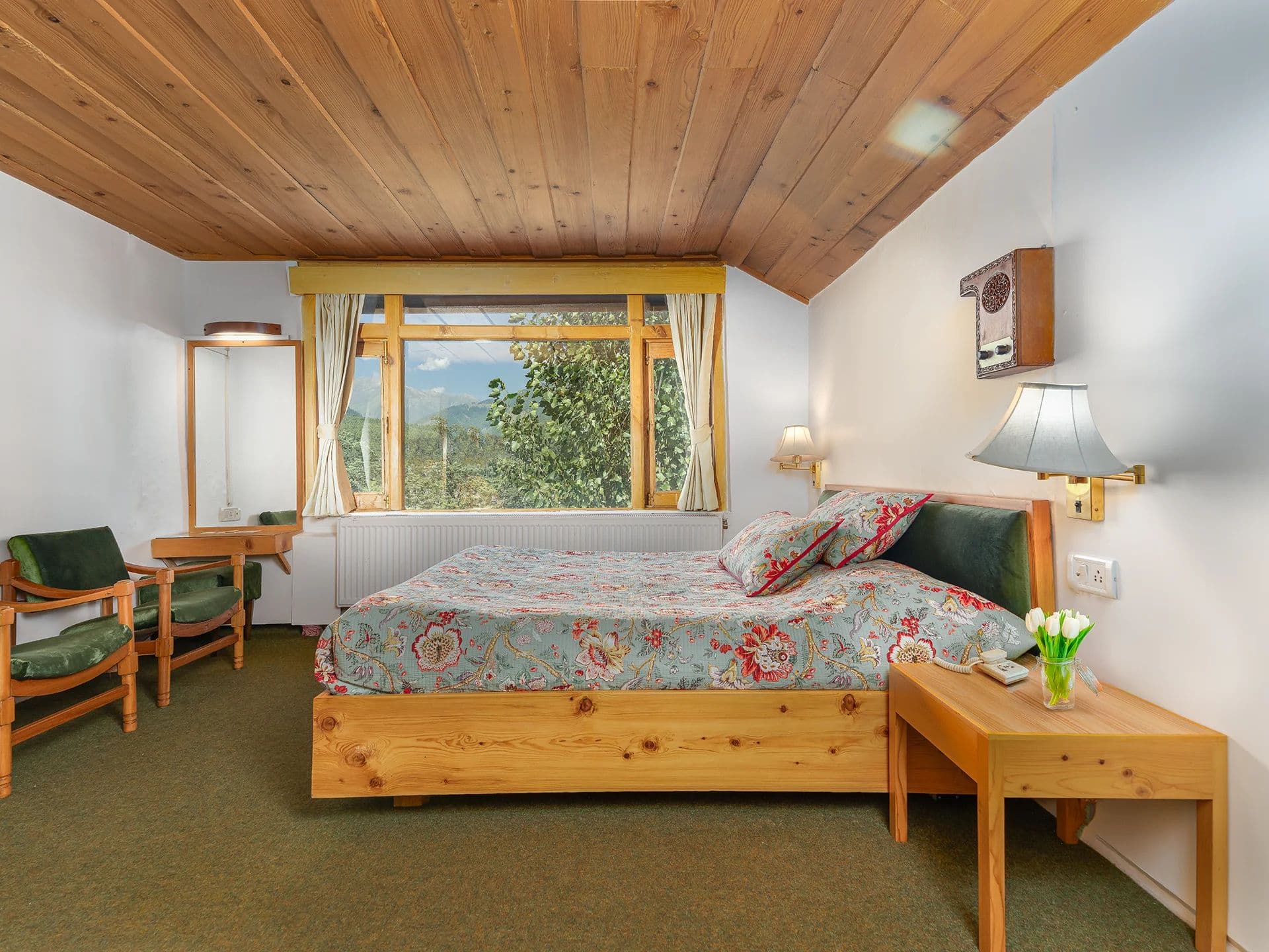 A Heritage double room at Pahalgam Hotel with a green bedspread and timber ceiling.
