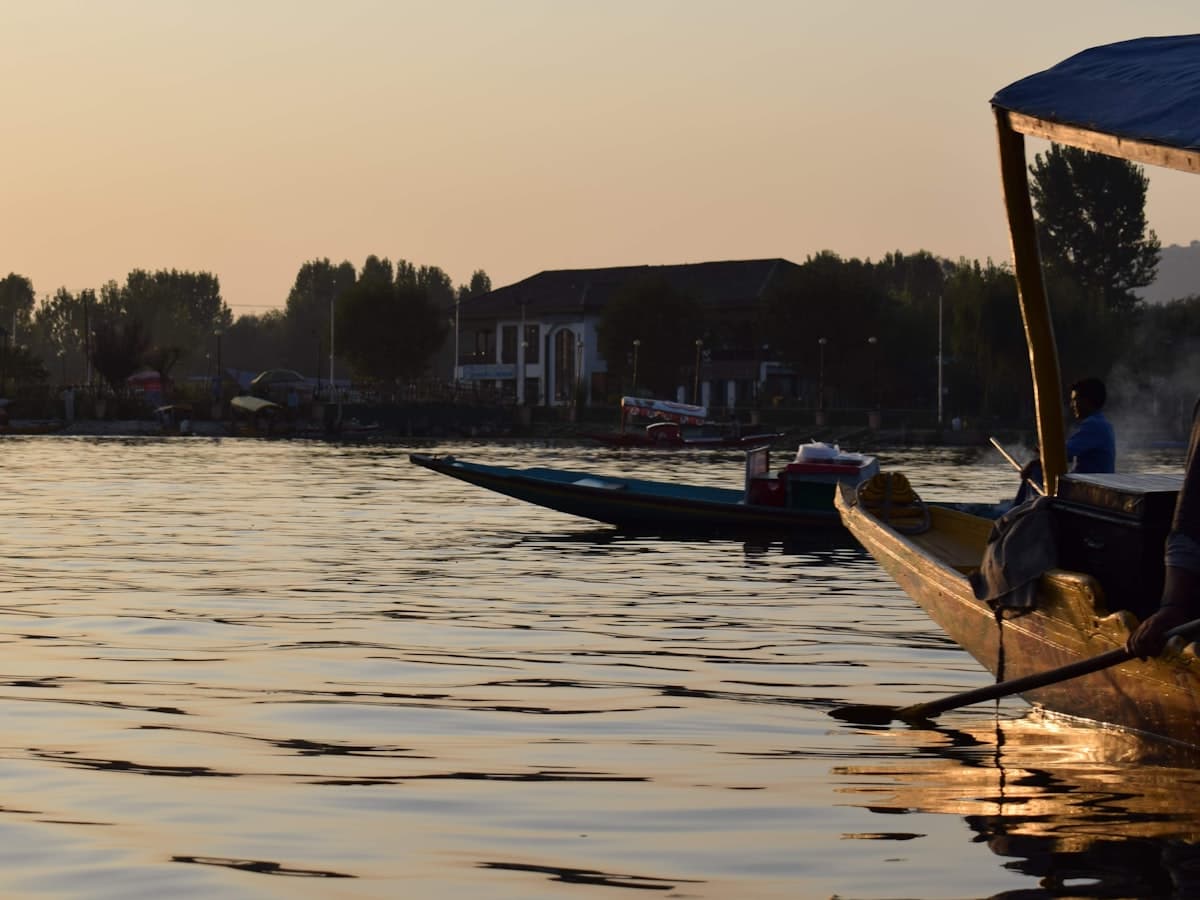 Wooden boats moored on Dal Lake in Srinagar under a sunset sky.