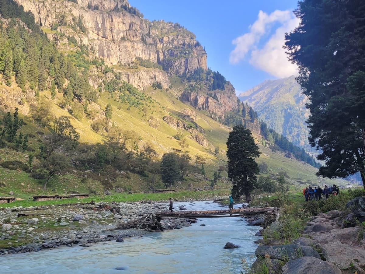 A river running through the green Sonamarg valley between mountains.