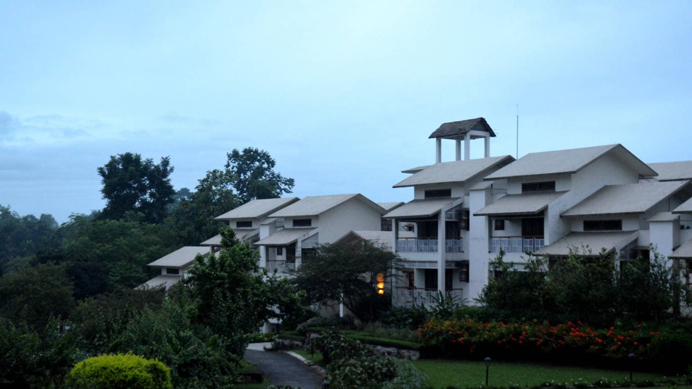 The pitched-roof resort buildings of IORA - The Retreat set among lawns near Kaziranga.