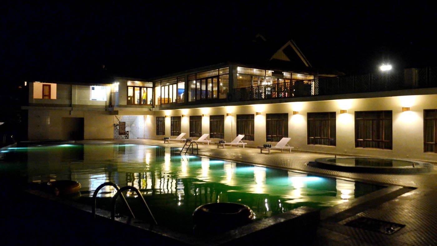 The outdoor pool lit at night below the main building at IORA - The Retreat.
