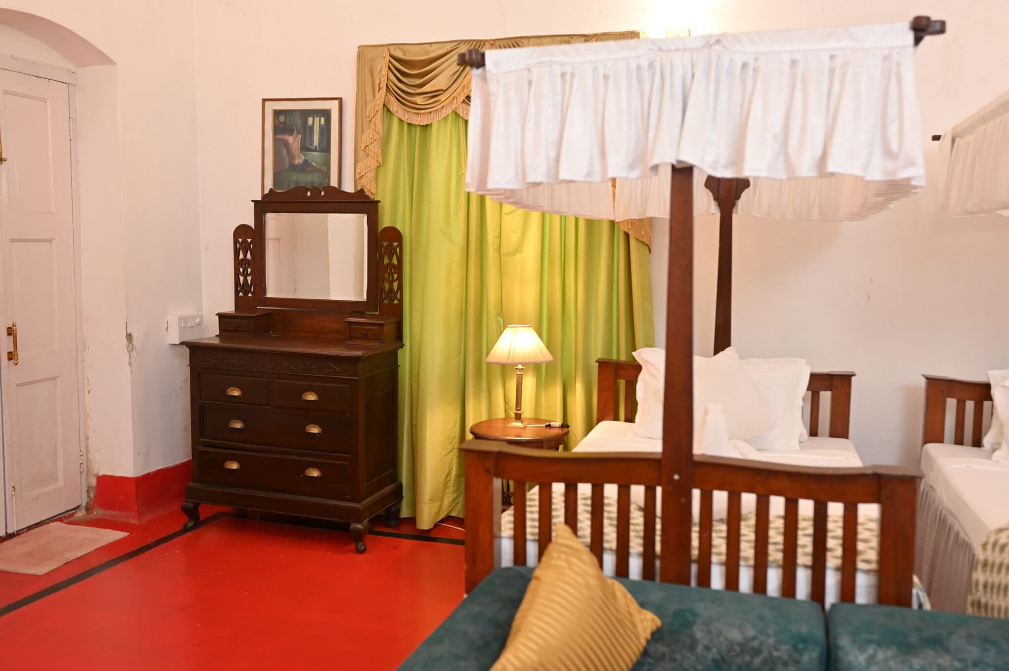 A second guest room at Thengal Manor with a four-poster bed and an antique dressing table.