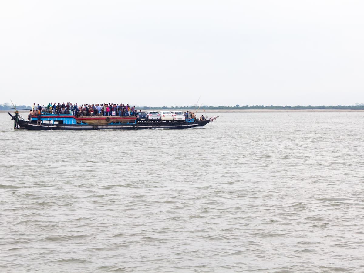 A crowded wooden ferry packed with passengers crosses the wide Brahmaputra towards Majuli island, Assam.