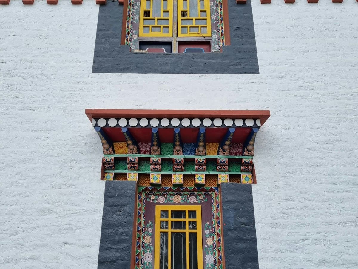 A whitewashed Buddhist monastery building with a red roof on a ridge in the Pelling area of West Sikkim.