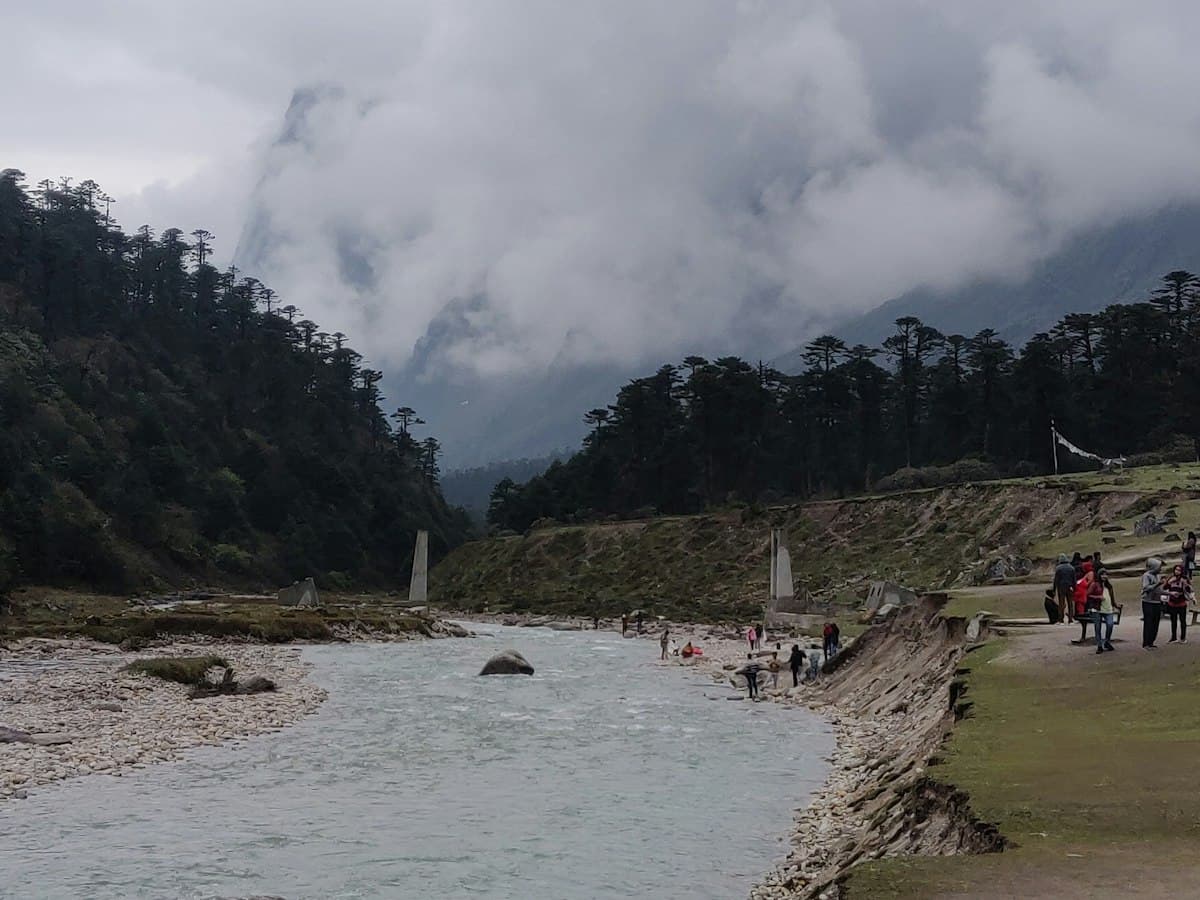 A wide braided river running through a broad meadow valley ringed by mountains, in the Yumthang area of North Sikkim.
