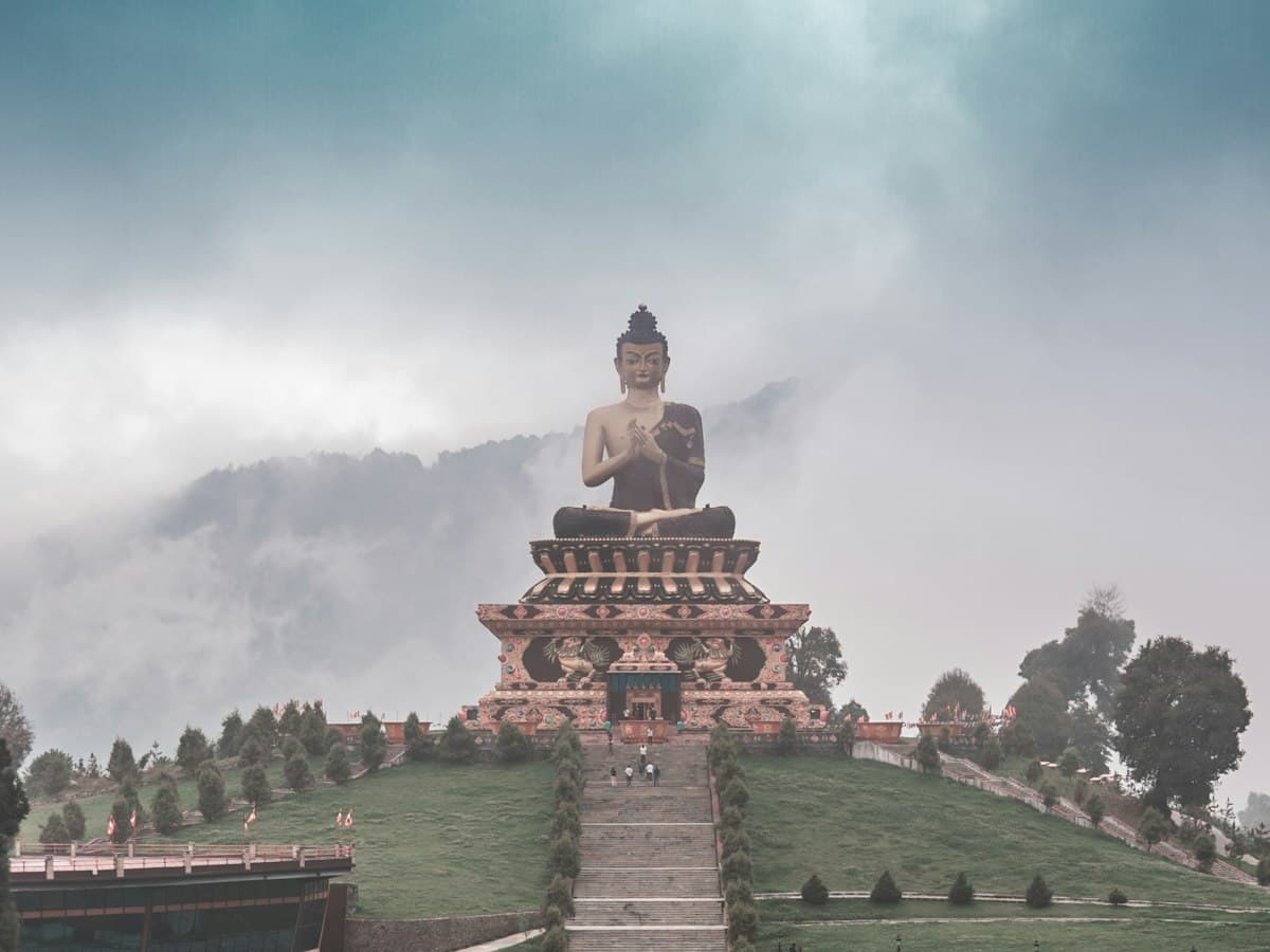The gold-coloured Great Buddha statue at Tathagata Tsal (Buddha Park), Ravangla, South Sikkim, set against forested hills.