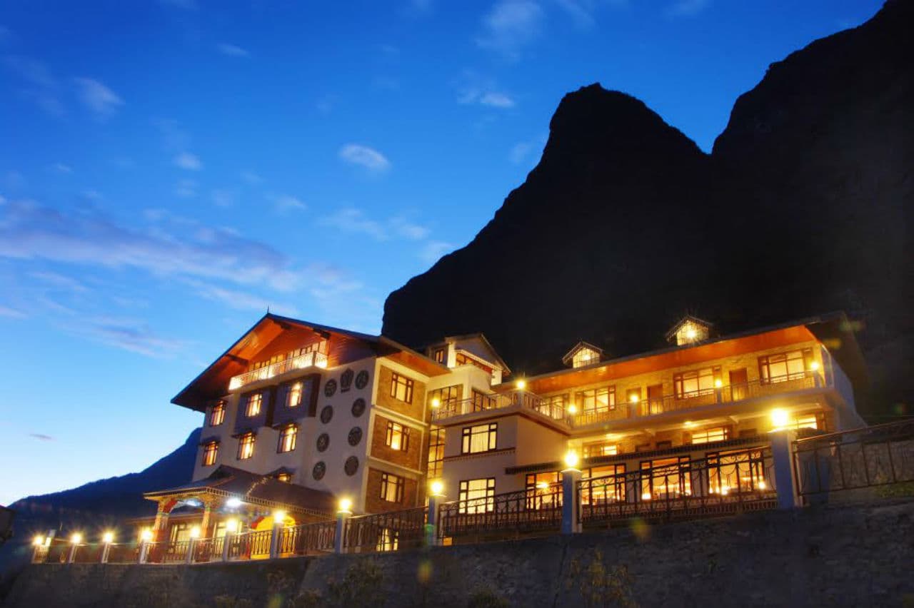 Yarlam Resort, Lachung, lit up at dusk beneath a Himalayan peak.