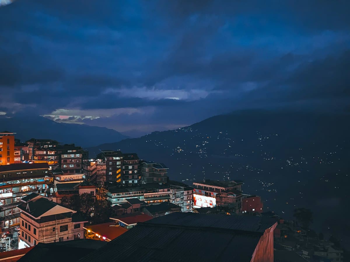 The lights of Gangtok spread across a Himalayan ridge at night, seen from an elevated viewpoint.