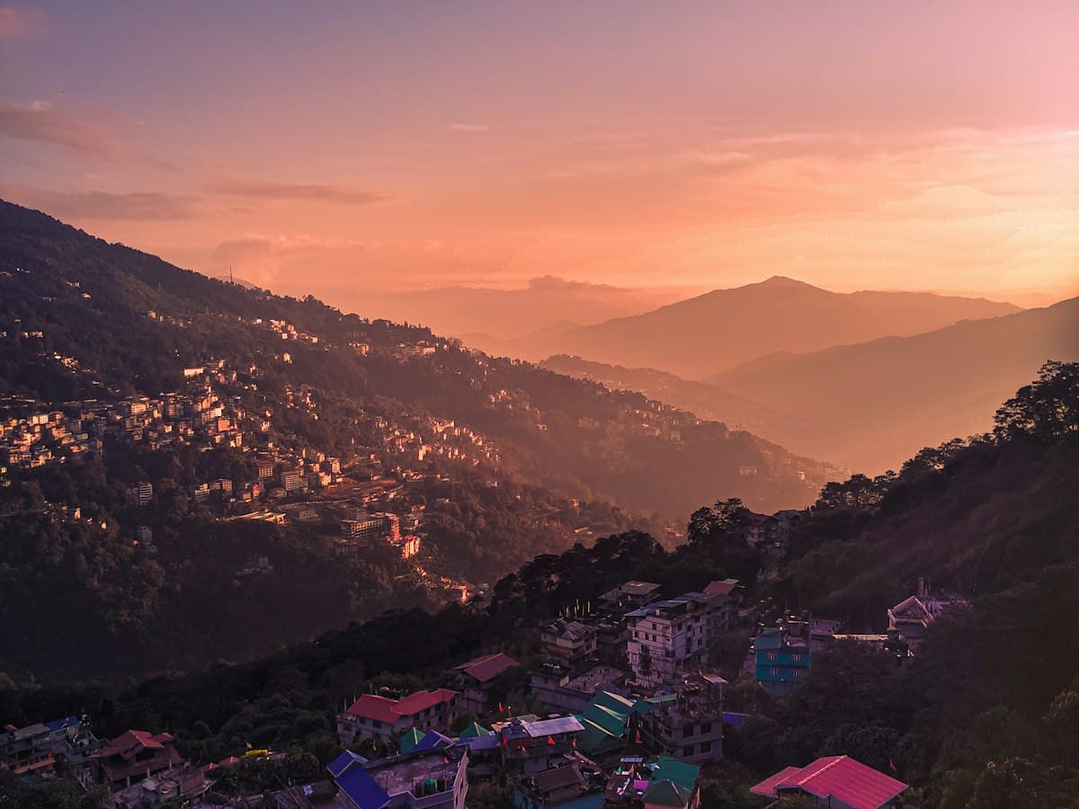 The hillside town of Gangtok silhouetted against a golden Himalayan sky at first light.