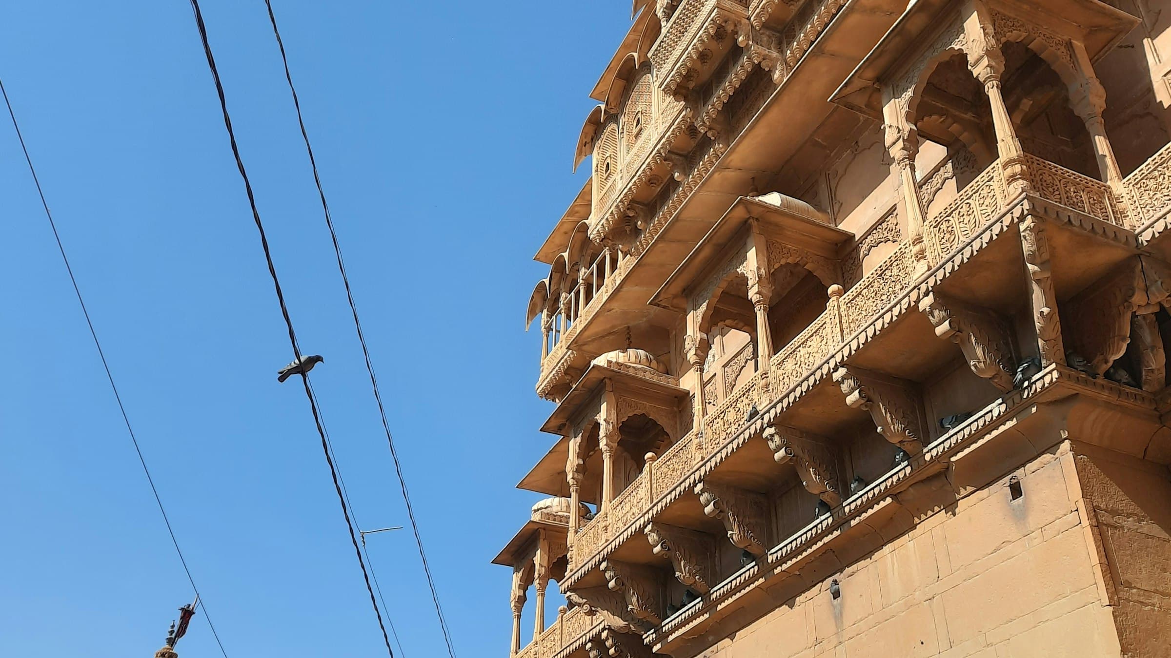 The golden sandstone walls and balconied buildings of Jaisalmer Fort under a clear sky in Rajasthan.