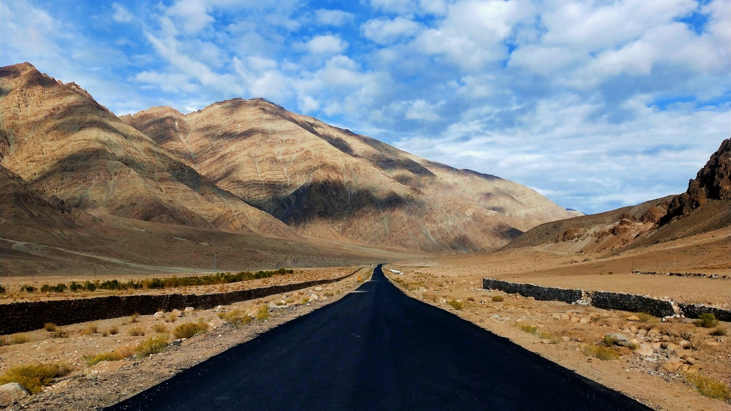 A long empty road runs through the barren mountain desert on the Leh to Mahe route in Ladakh.