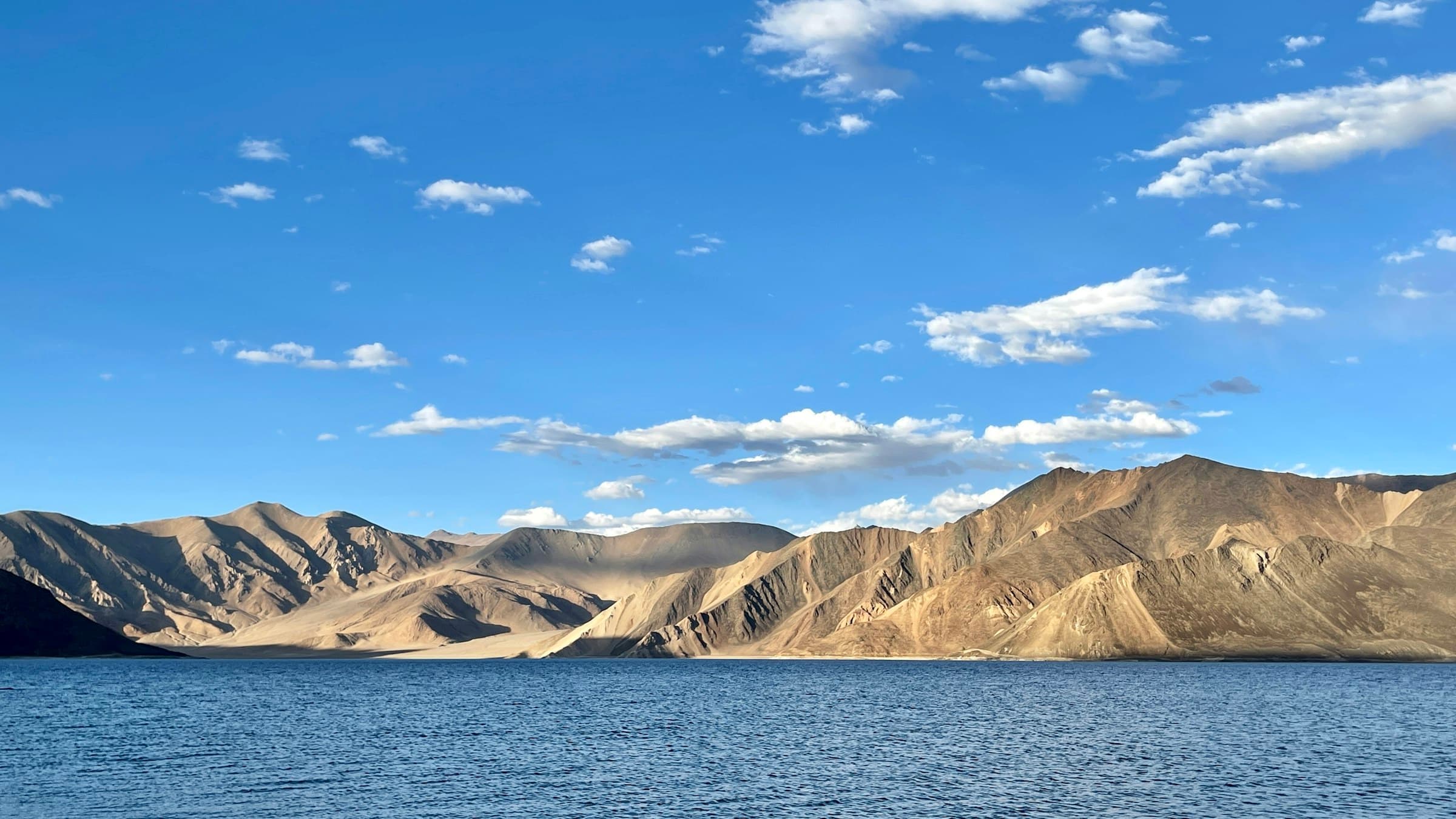 The turquoise water of Pangong Tso lies against bare brown mountains in Ladakh, India.