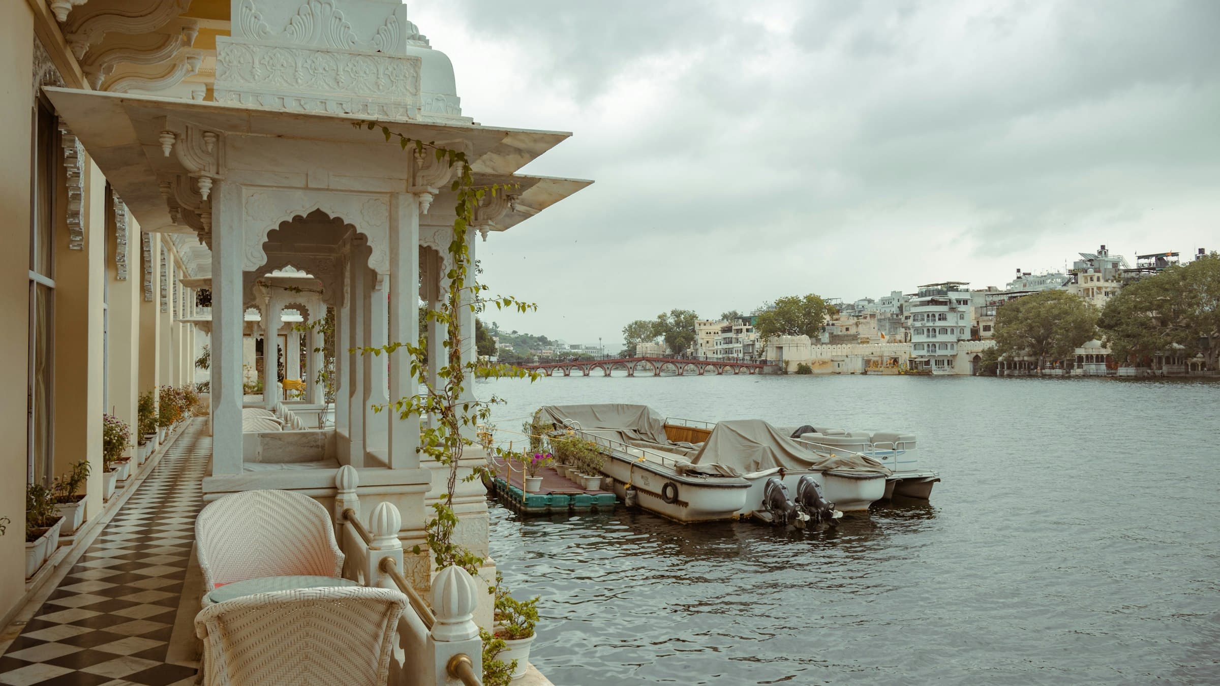 Boats rest on Lake Pichola in front of Udaipur's lakeside heritage buildings in Rajasthan.
