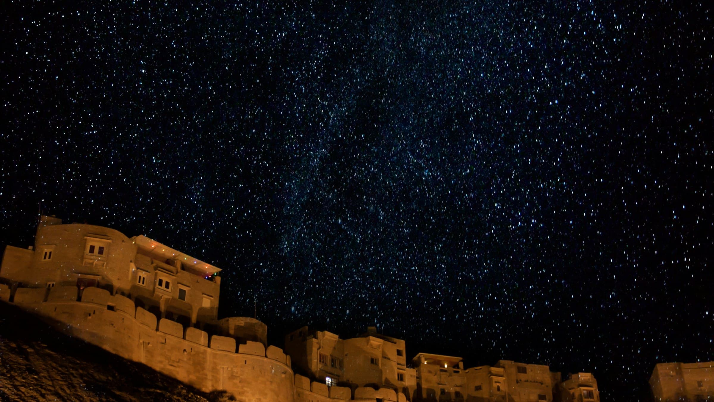 The sandstone ramparts of Jaisalmer Fort stand under a star-filled night sky in Rajasthan.