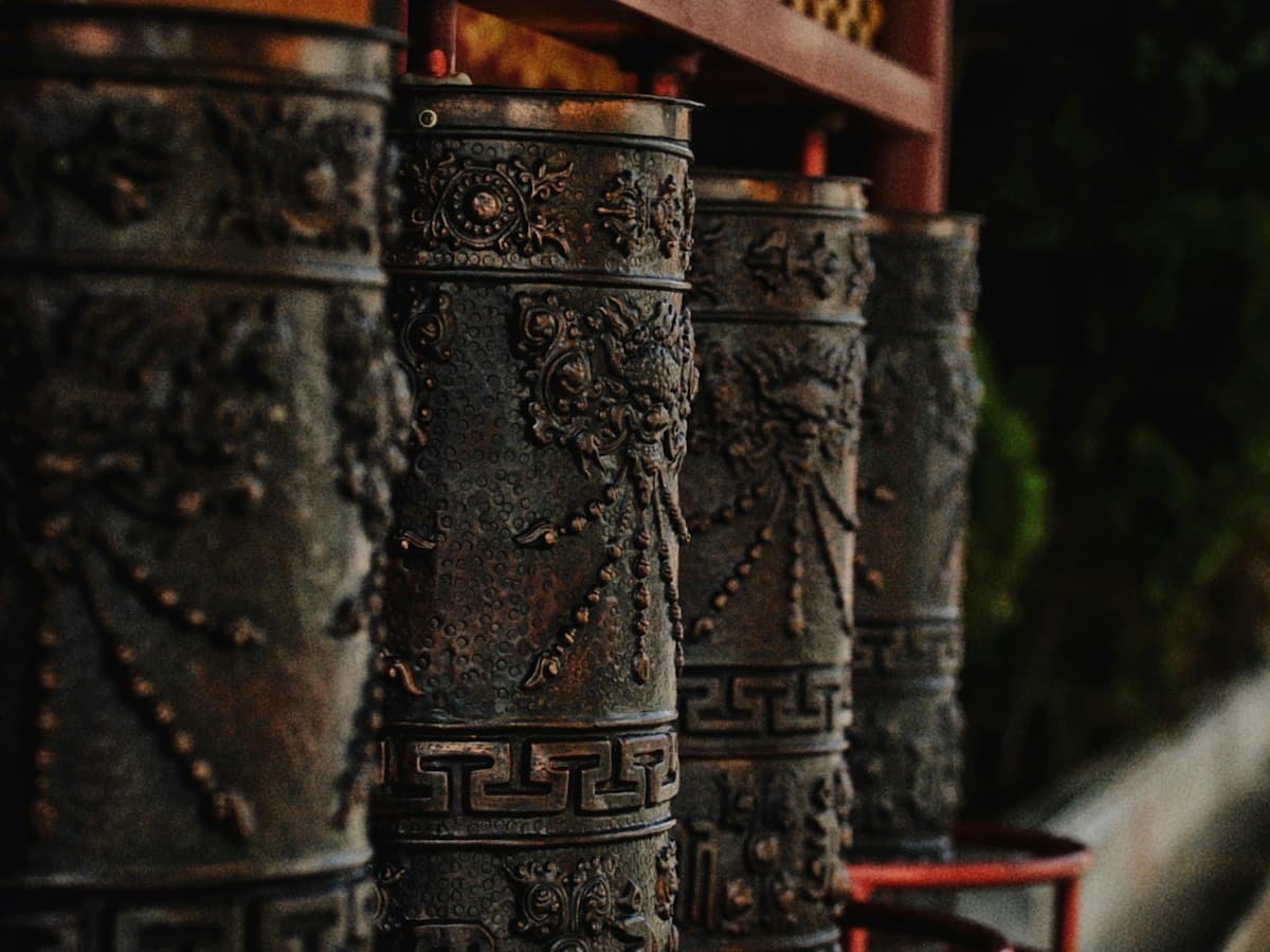 A row of ornate Tibetan prayer wheels with carved script, as found at McLeodganj's Tsuglagkhang complex.