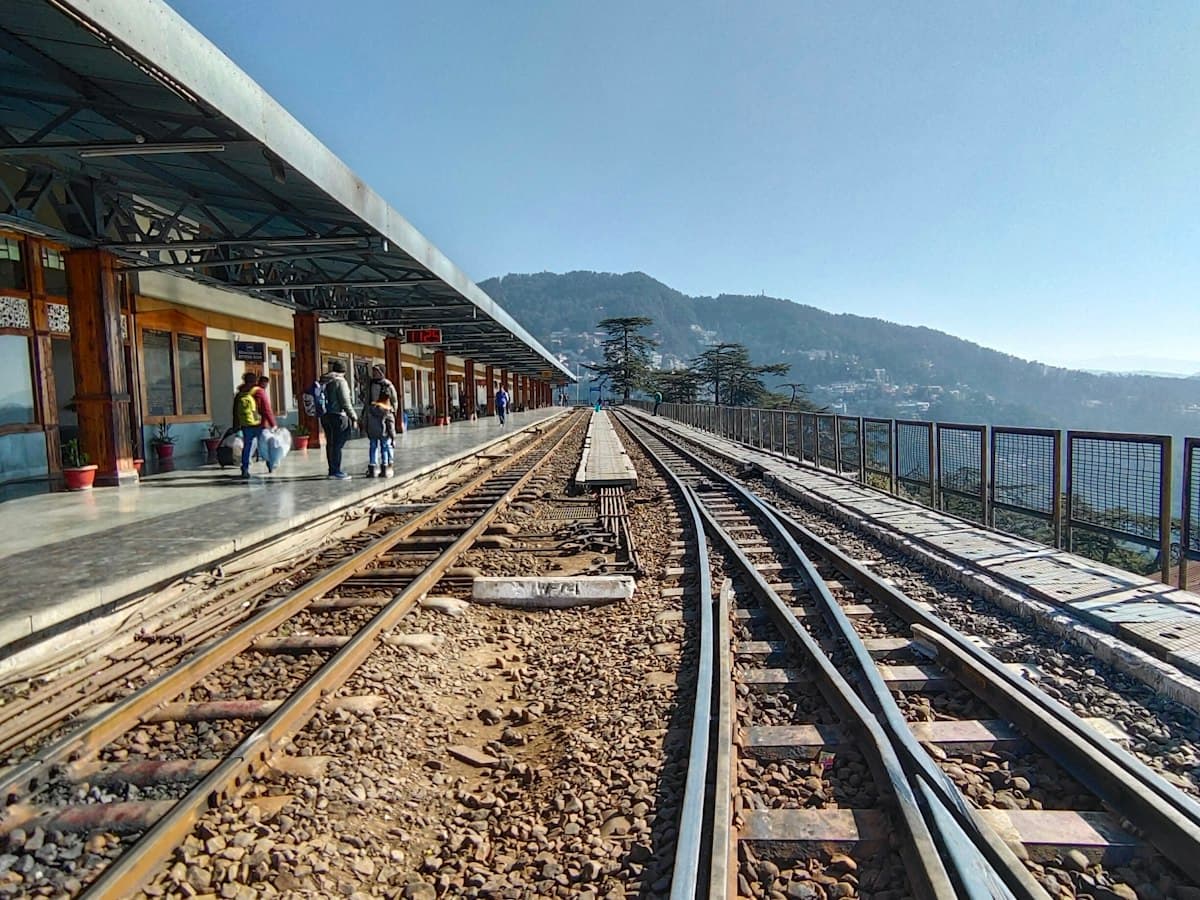 Passengers wait beside the narrow-gauge train at a Kalka-Shimla railway platform.