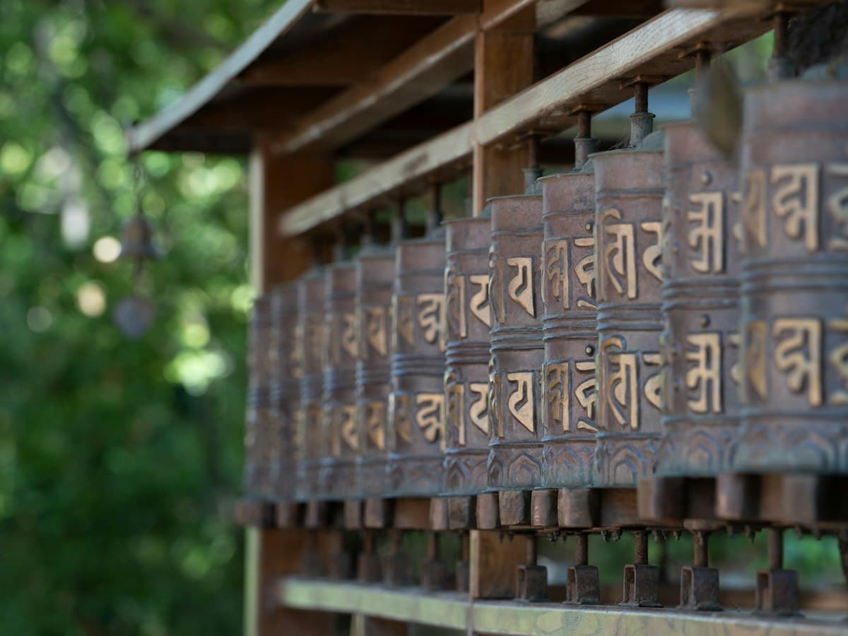 A long row of Tibetan prayer wheels carved with script, spun by pilgrims in McLeodganj.