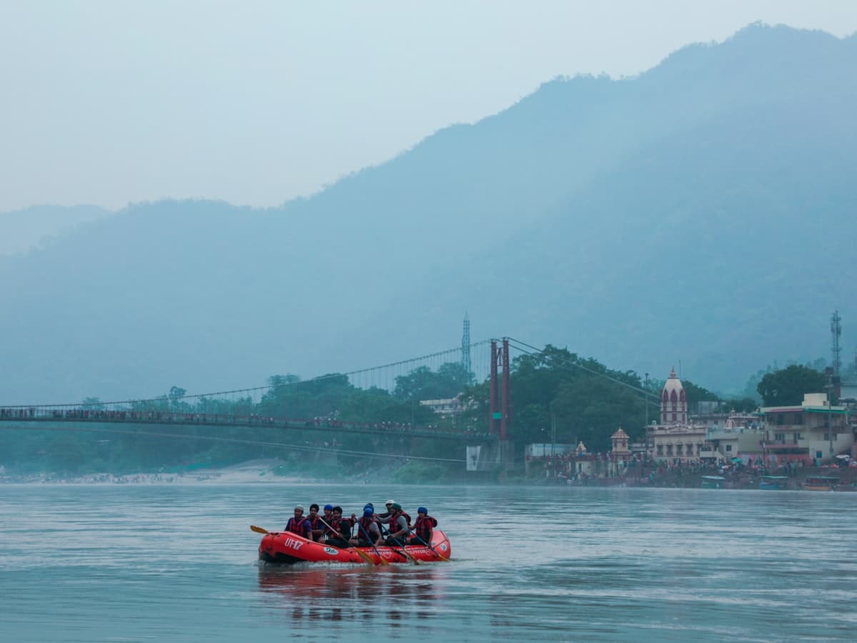 A raft of helmeted paddlers rides whitewater on a fast Himalayan river.