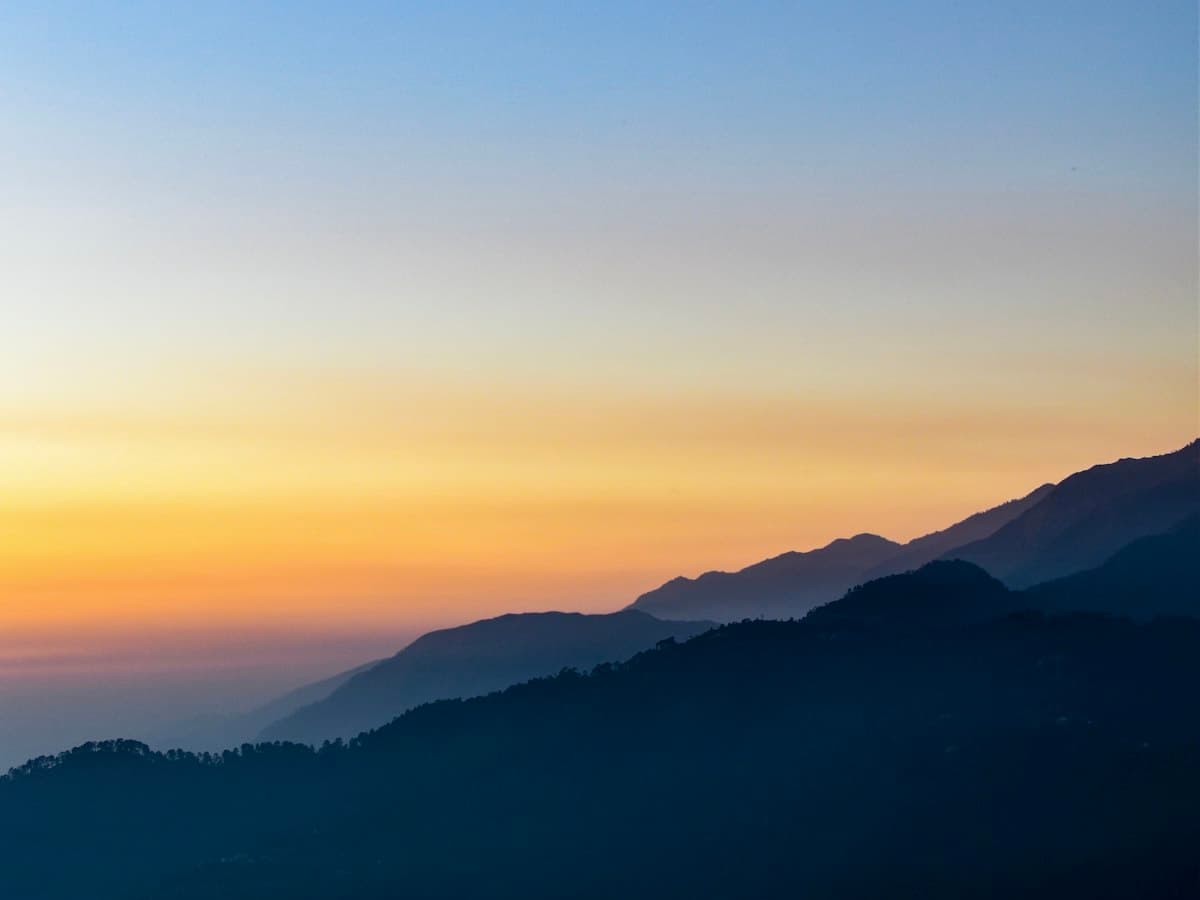 Warm late light falls over a receding Himalayan mountain range at sunset.