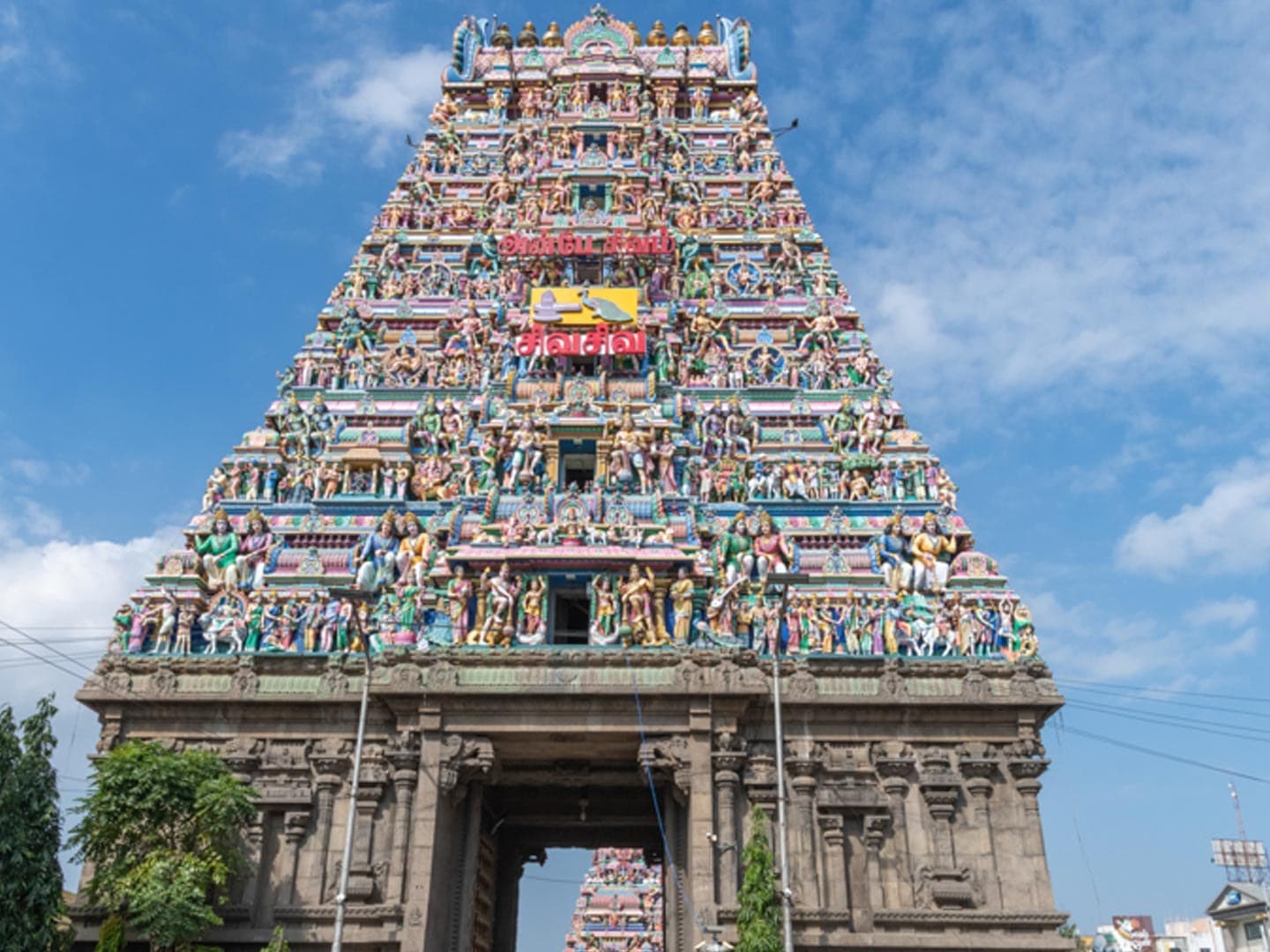 The tall, brightly painted gopuram tower of the Kapaleeshwarar Temple in Mylapore, Chennai, against a blue sky.