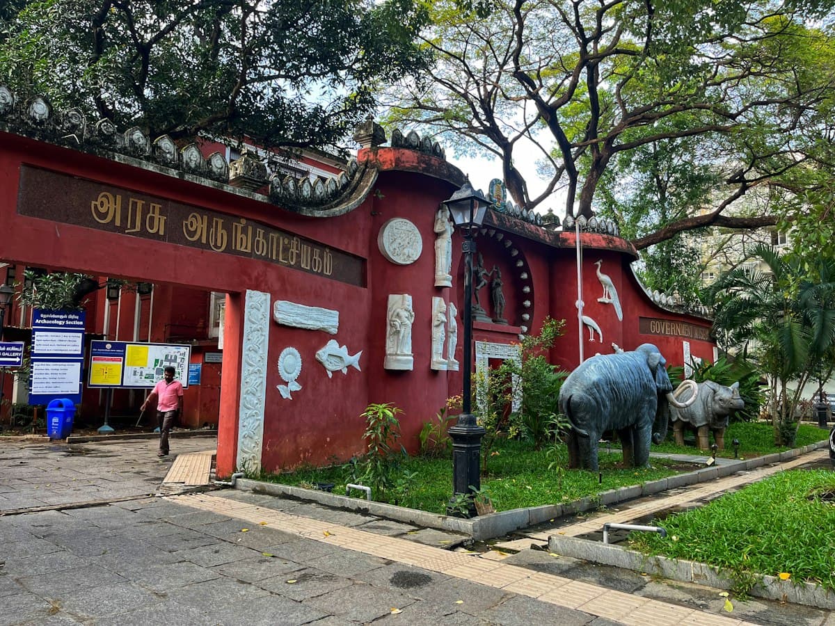 The red Indo-Saracenic entrance of a museum flanked by elephant and rhino statues, Chennai.