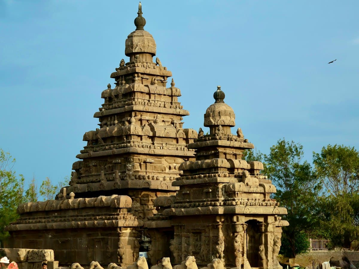 The beachfront Shore Temple at Mahabalipuram with tiered stone towers against a clear blue sky.