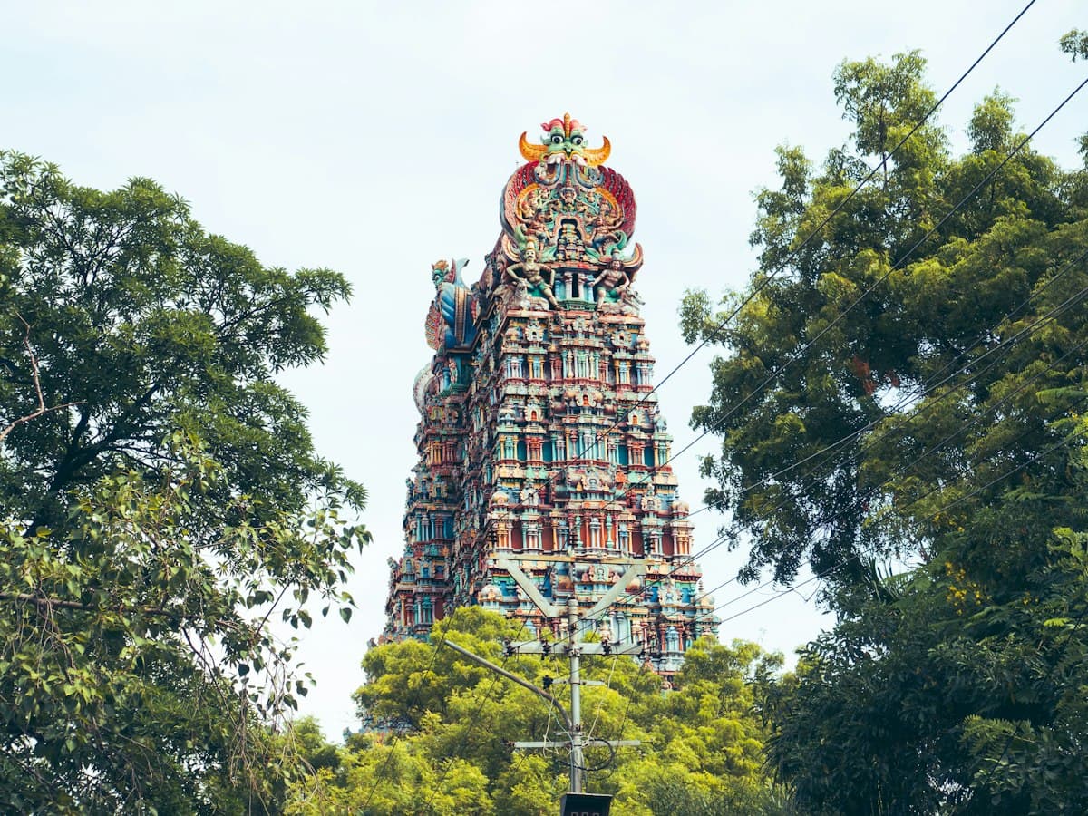 A tall figure-covered gopuram tower of the Meenakshi Amman Temple in Madurai, Tamil Nadu.
