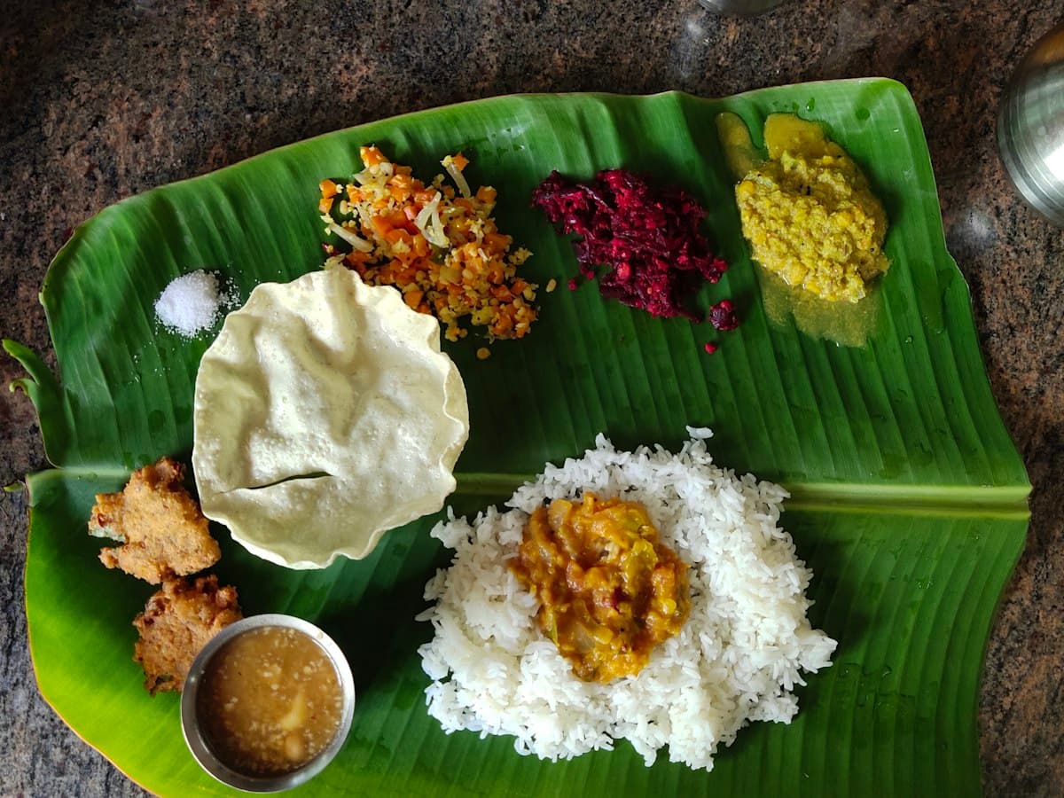 A traditional South Indian meal of rice and side dishes served on a large green banana leaf.