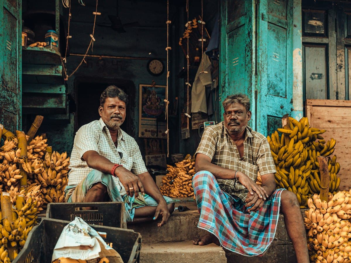 Two vendors smile beside stacks of bananas at a street market in Chennai, Tamil Nadu.